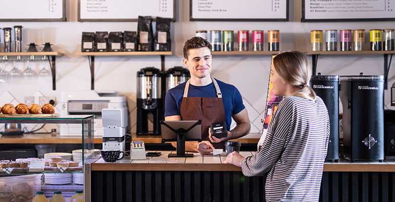 Mužský barista v kavárně obsluhující zákaznici