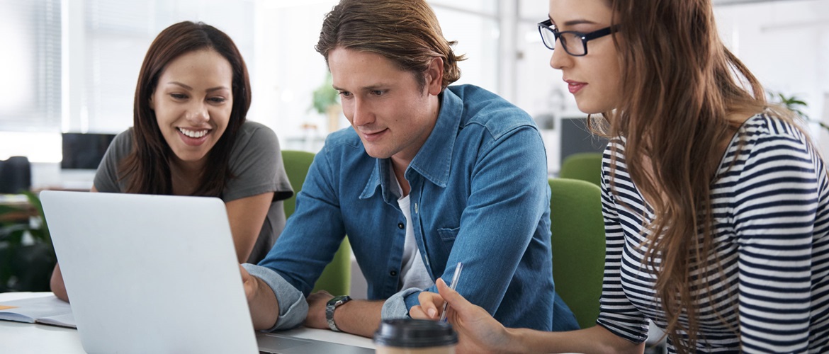 Three young colleagues work together on a laptop