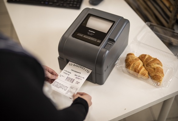 Detail tiskárny štítků Brother, která tiskne štítek pro balíček croissantů v provozní kanceláři lahůdek, pekárně nebo kavárně