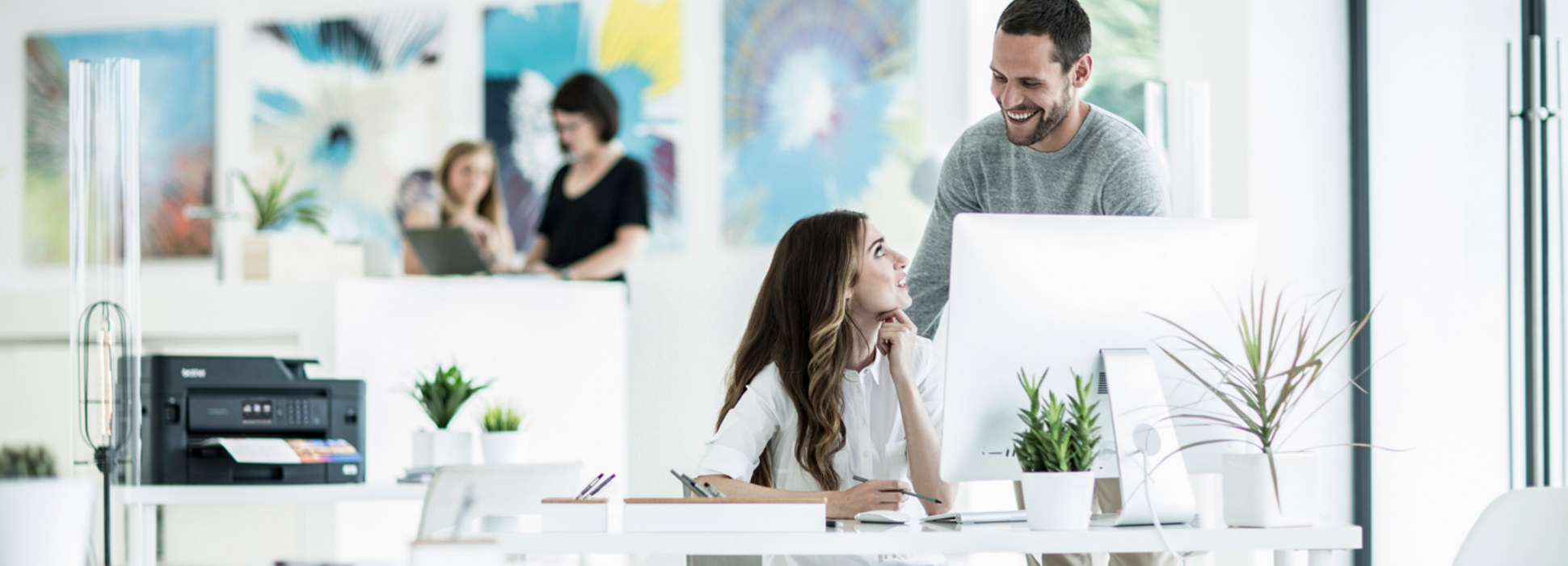 Coworkers smiling with Brother printer in the background
